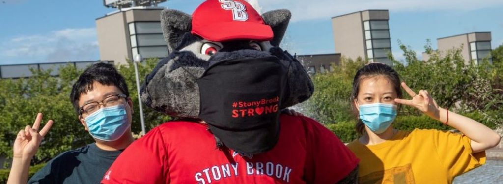 Stony Brook University, Stony Brook, NY: Wolfie and students pose in their masks in front of the Wang Center. Credit: Stony Brook University/John Griffin.