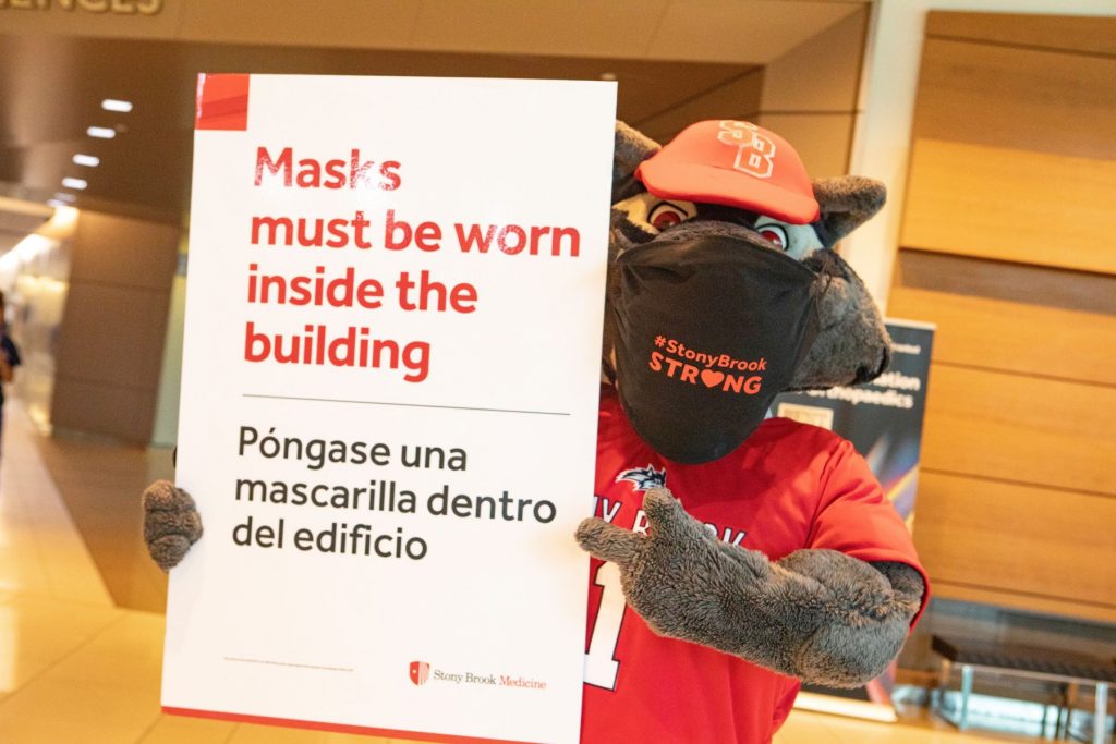 Wolfie wearing a mask and holding signage.