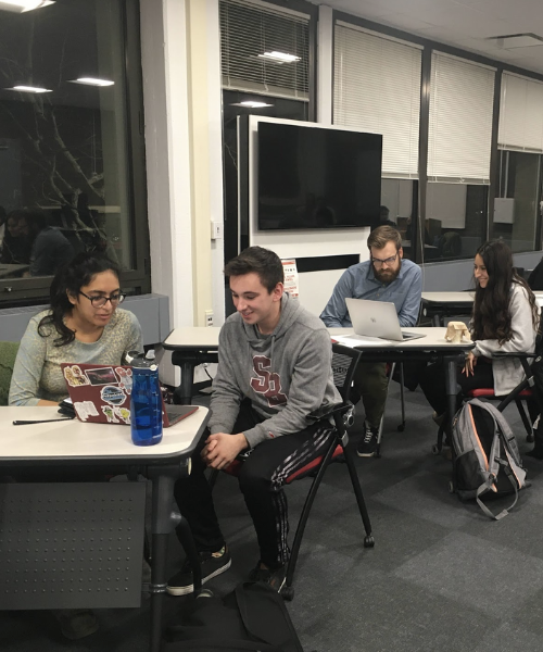 Students speaking with writing tutors in the library