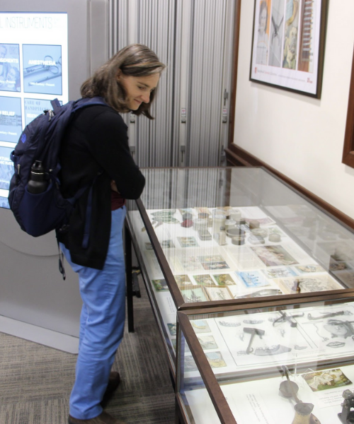 Person looking at objects in display case at the Prelec Memorial Lecture